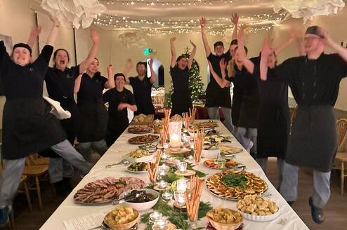 Kitchen team standing around table full of food