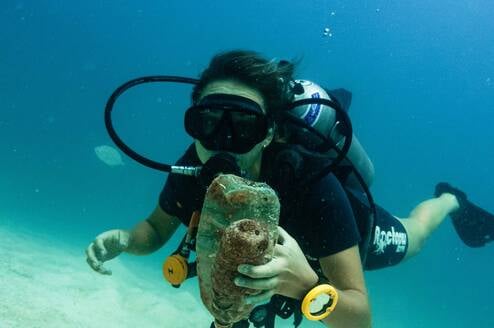 a scuba diver holds trash 