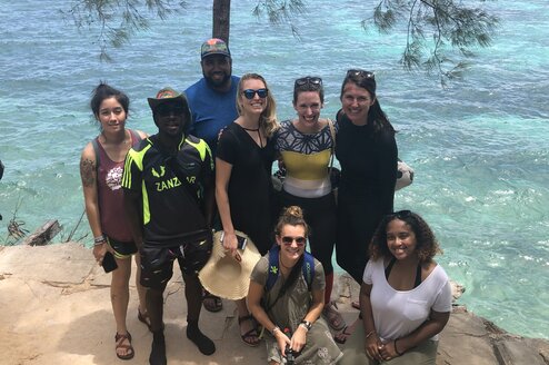 A group of students posing in front of a body of water.