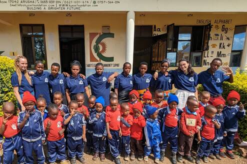 Teachers, volunteers and students posing in front of the school