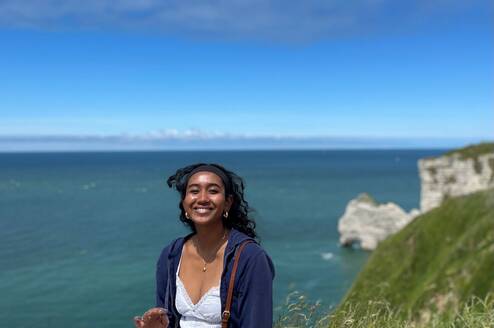 Student sitting on a hill overlooking a body of water, enjoying all that France has to offer