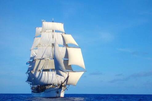 A tall ship with all sails up in the open ocean