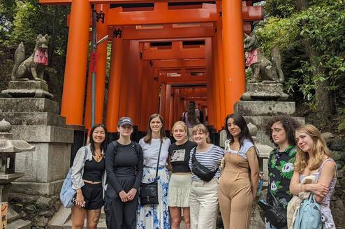 group smiling in front or red gate