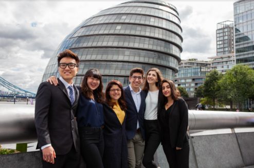 Interns stand together and smile in London.