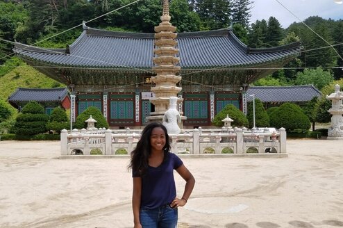 A young woman poses in front of a temple in South Korea.