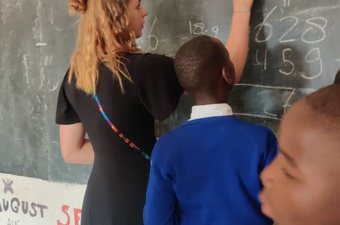 Volunteer teaching a class of eager students in a Tanzanian school