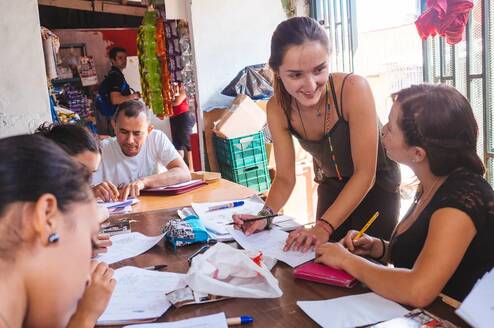 A teacher works with a group of adults at a table.