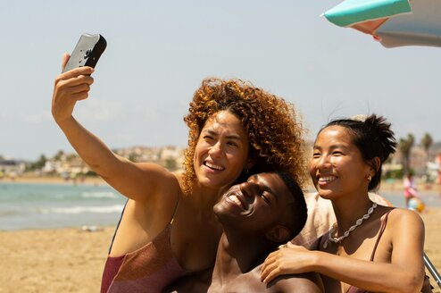 A group of friends take a selfie on the beach.
