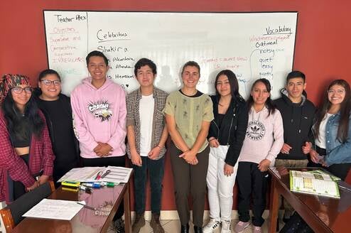 A teacher and their students near the whiteboard in class