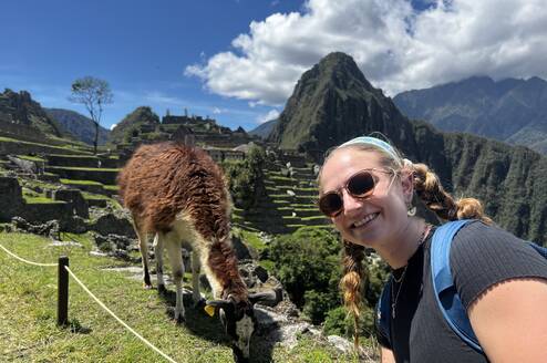 Girl smiling and taking a selfie in front of a llama at Machu Picchu 