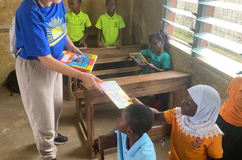 Volunteer handing book to student