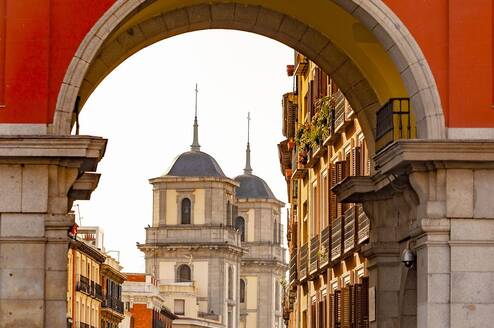 Red archway looking out on historic building in Spain