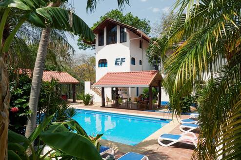 EF Tamarindo campus in Costa Rica with a pool surrounded by palm trees, lounge chairs, and tropical buildings where students live and study abroad.