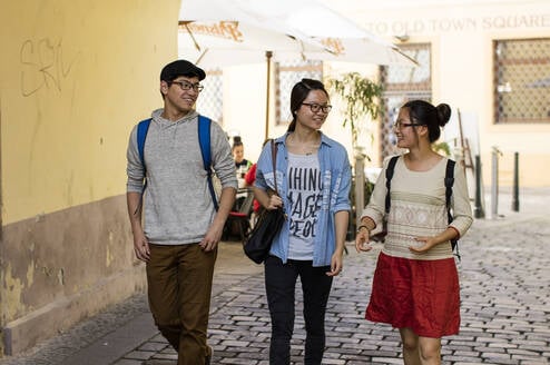 Three students walk on the street.