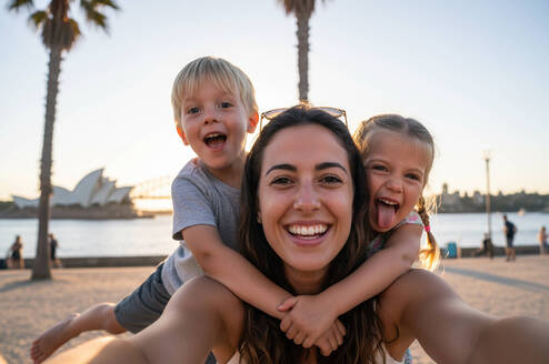 Smiling host parent with two young children outdoors in Australia