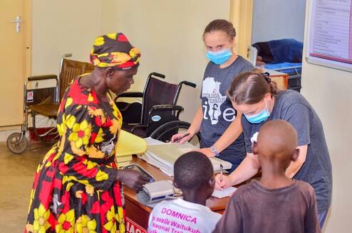 Volunteers and local staff documenting patient information inside the Maisha clinic during a medical care day