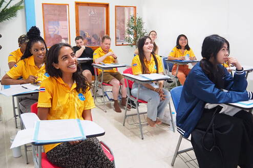 A group of international students sitting in a vibrant classroom during an orientation session in Sukhothai, Thailand.