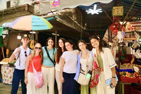 Students smiling in front of a market