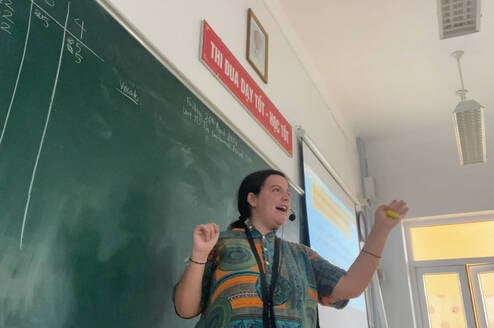 Female TEFL teacher in action wearing microphone and gesturing with hands.