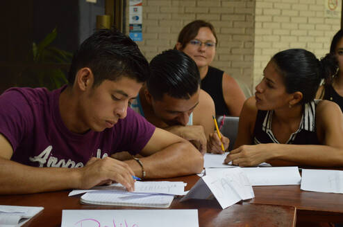 People working with worksheets around a wooden table.