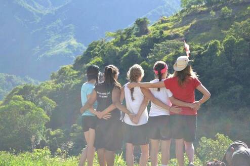 Group of volunteers hiking and hugging in mountain scenery
