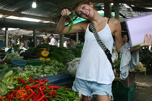 a teacher poses with a chili in a thailand market