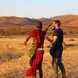 a white man and a Maasai man standing in the savannah