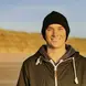 Niall Coombes wearing a black beanie and black zip up jacket smiling 