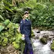 Vanessa Rees standing in a stream in a jungle with a hat on smiling