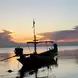 A boat on the ocean with the sun setting behind it