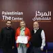 Woman holding a certificate standing between two men in front of a maroon wall