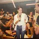 Candida speaking into a microphone while a student smiles and listens