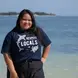 Tania smiling at the camera in front of a beautiful turquoise blue ocean back drop