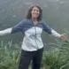 Maggie stands with arms wide above a river canyon