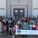 image of smiling students and staff in front of building 