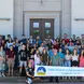 group of students and teachers in front of colorful banner