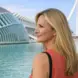 Blonde woman looking across water near a bridge