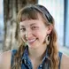 I'm female with light brown/dirty blonde hair with bangs, wearing a denim button down sleeveless dress, a headband, and big circular earrings.