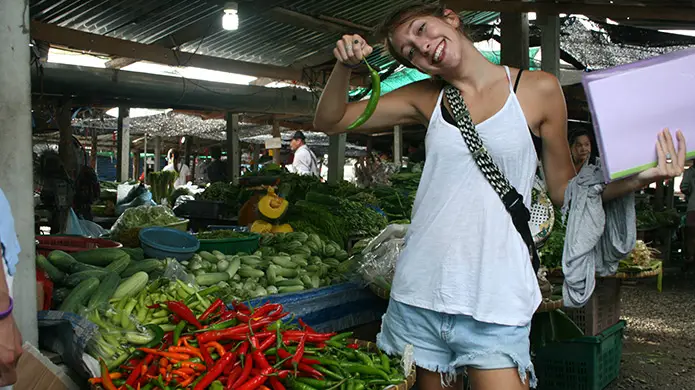 a teacher poses with a chili in a thailand market