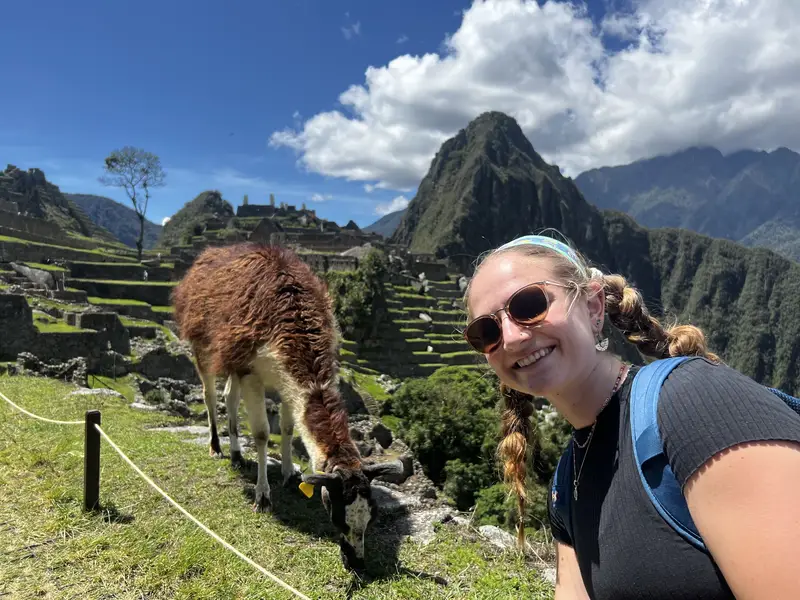 Girl smiling and taking a selfie in front of a llama at Machu Picchu 