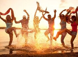 Happy people splashing in the ocean at sunset.