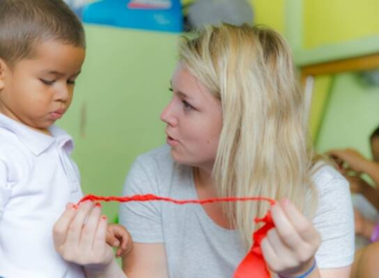 Volunteer assisting a young boy with his ribbon in Ecuador