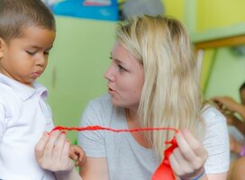 Volunteer assisting a young boy with his ribbon in Ecuador