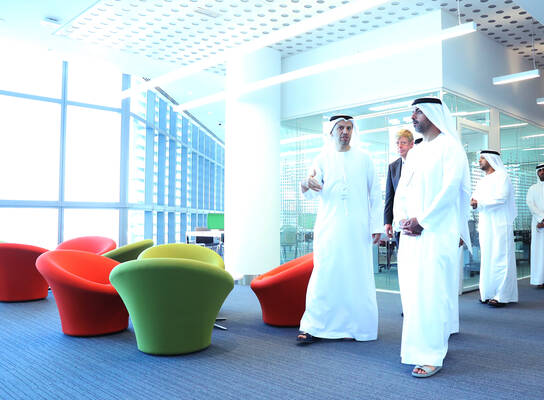 Khalifa University directors and leadership walk through the modern campus in traditional Arabic clothes. 