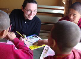 Volunteer in Nepal looking at book with student