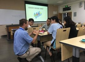 students around a table learning with powerpoint in the background