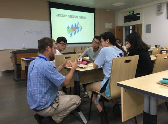 students around a table learning with powerpoint in the background