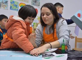 One of the alumni's from this program is pictured working with a student in China.