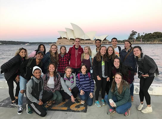 Students striking a pose in front of the famous Sydney Opera House.