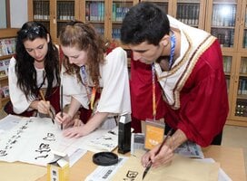 three young students writing Chinese characters with chinese brush in Chinese learning class